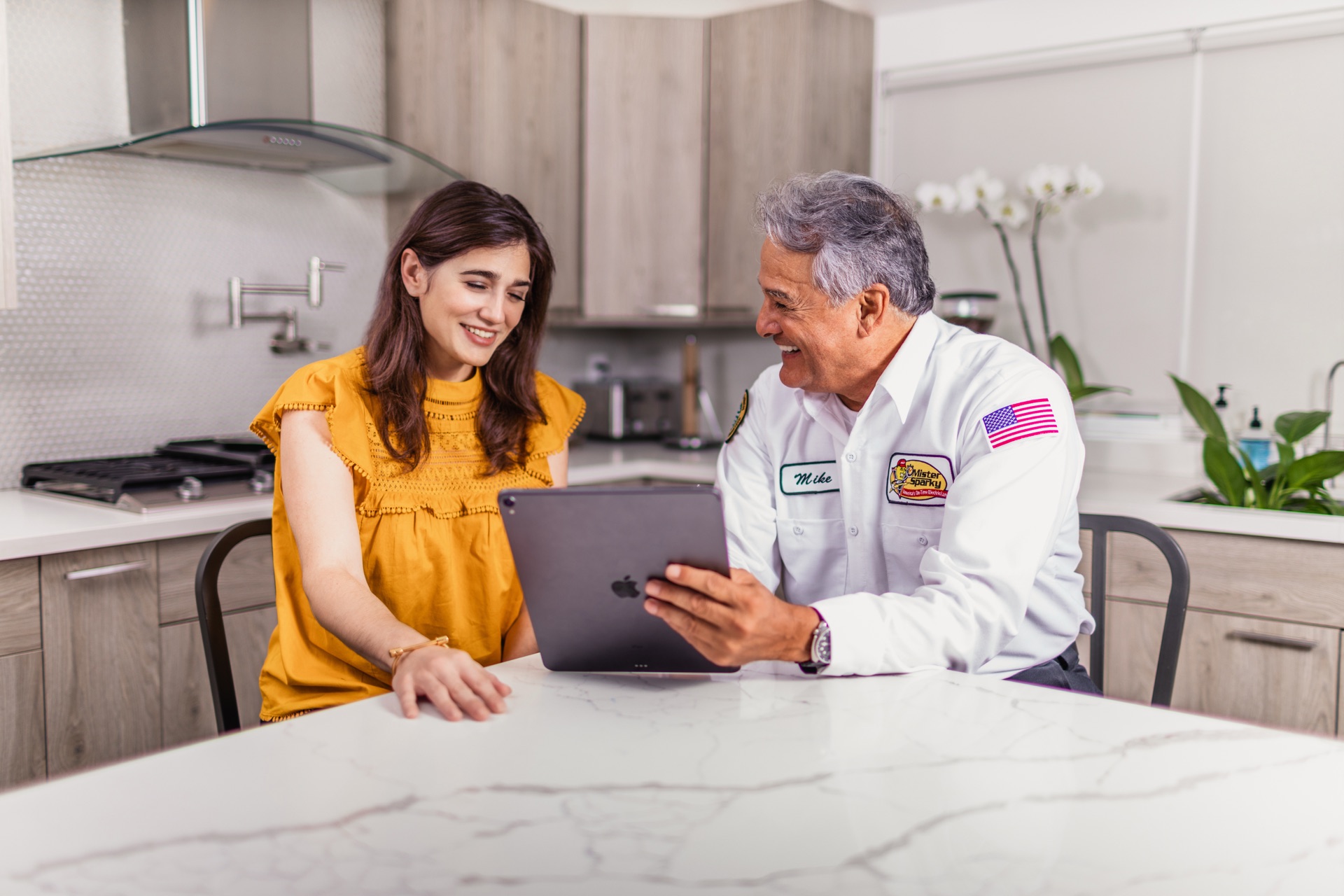 Mr Sparky technician reviewing service options with a homeowner at her kitchen island